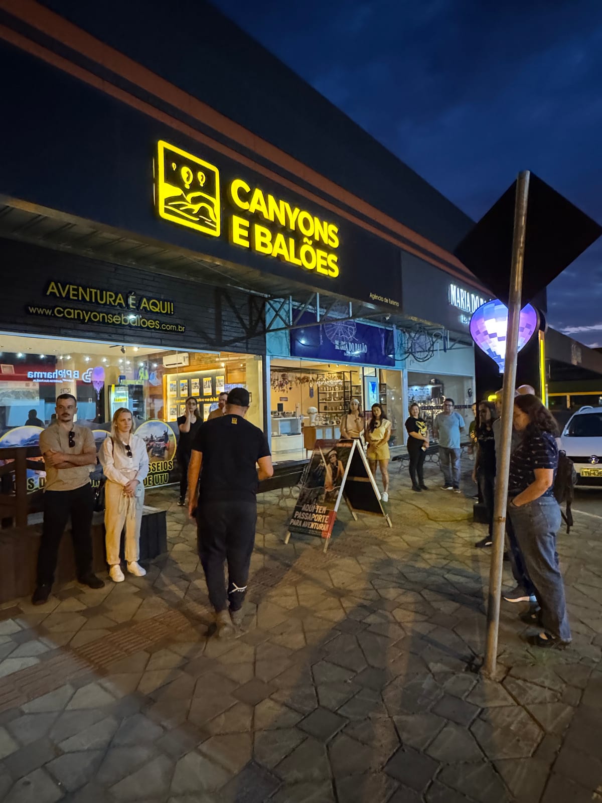 Fachada iluminada da loja da Canyons e Balões em Praia Grande, com clientes na entrada